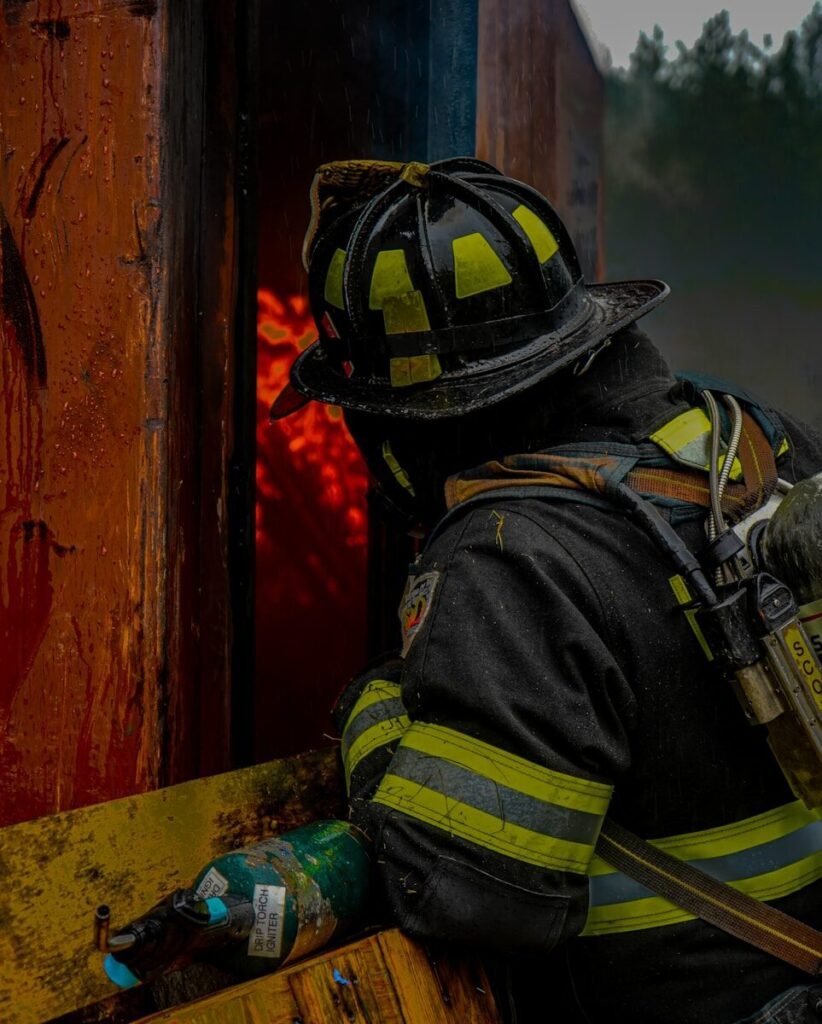 Firefighter in gear looks into burning structure