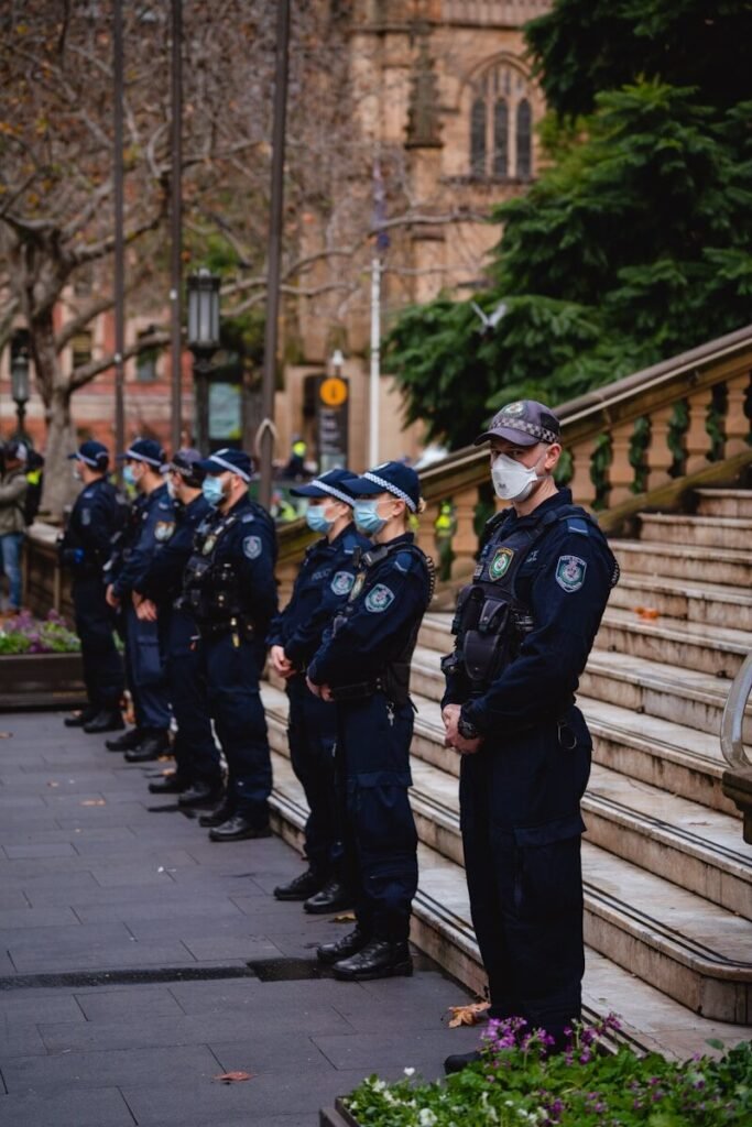 3 men in black uniform standing on sidewalk during daytime